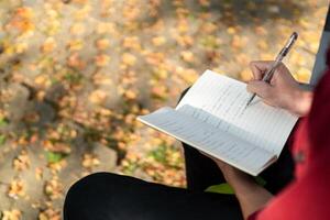 asiatico Università alunno studiando su il computer portatile a città universitaria all'aperto parco. uomo scrittura su un' Nota libro e Lavorando su il computer portatile. educativo concetto foto