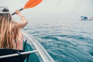 donna nel kayak indietro Visualizza. contento giovane donna con lungo capelli galleggiante nel trasparente kayak su il cristallo chiaro mare. estate vacanza vacanza e allegro femmina persone rilassante avendo divertimento su il barca foto