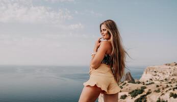 donna viaggio mare. contento turista assunzione immagine all'aperto per ricordi. donna viaggiatore sembra a il bordo di il scogliera su il mare baia di montagne, condivisione viaggio avventura viaggio foto