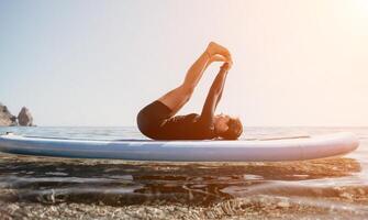 donna cenare yoga. contento sportivo donna praticando yoga pilates su pagaia cenare tavola da surf. femmina allungamento fare allenarsi su mare acqua. moderno individuale femmina fricchettone all'aperto estate sport attività. foto