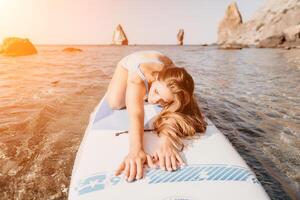 donna mare sup. vicino su ritratto di contento giovane caucasico donna con lungo capelli guardare a telecamera e sorridente. carino donna ritratto nel un' blu bikini in posa su cenare tavola nel il mare foto