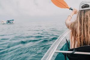 donna nel kayak indietro Visualizza. contento giovane donna con lungo capelli galleggiante nel trasparente kayak su il cristallo chiaro mare. estate vacanza vacanza e allegro femmina persone rilassante avendo divertimento su il barca foto