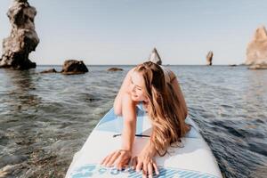 donna mare sup. vicino su ritratto di contento giovane caucasico donna con lungo capelli guardare a telecamera e sorridente. carino donna ritratto nel un' blu bikini in posa su cenare tavola nel il mare foto