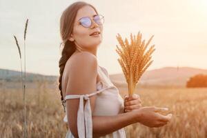 donna Grano campo. agronomo, donna contadino dai un'occhiata d'oro maturo orzo picchi nel coltivato campo. un' donna è Tenere un' mazzo di Grano nel sua braccia. foto