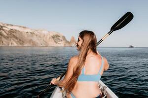 donna nel kayak indietro Visualizza. contento giovane donna con lungo capelli galleggiante nel kayak su calma mare. estate vacanza vacanza e allegro femmina persone rilassante avendo divertimento su il barca. foto