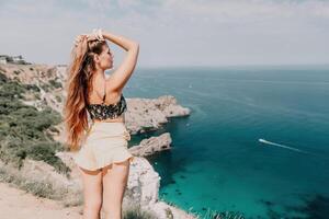 donna viaggio mare. contento turista godere assunzione immagine all'aperto per ricordi. donna viaggiatore sembra a il bordo di il scogliera su il mare baia di montagne, condivisione viaggio avventura viaggio foto