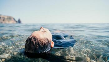 donna nuoto nel mare a tramonto, galleggiante su calma acqua indietro Visualizza. concetto di corpo Immagine e fitness, godendo un' sereno spiaggia. contento donna con Perfetto in forma corpo gode mare spiaggia foto