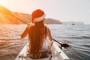 donna nel kayak indietro Visualizza. contento giovane donna nel Santa cappello galleggiante nel kayak su calma mare. estate vacanza vacanza e allegro femmina persone rilassante avendo divertimento su il barca. foto