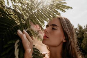 bellezza ritratto di contento donna avvicinamento. giovane ragazza odorare Cinese acacia rosa fioritura fiori. ritratto di giovane donna nel fioritura molla, estate giardino. romantico vibrazione. femmina e natura foto