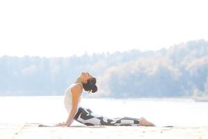 giovane donna fare yoga vicino lago all'aperto, meditazione. sport fitness e esercizio nel natura. autunno tramonto. foto