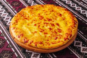 delizioso formaggio Pizza su tradizionale tovaglia foto