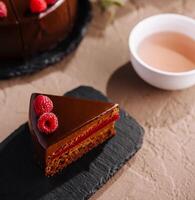 elegante lampone cioccolato torta fetta con tè impostare foto