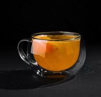 bicchiere boccale di caldo agrume tè su buio sfondo foto