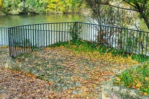 si affacciano sul fiume con ringhiera e foglie secche a terra foto