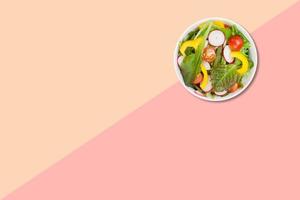vista ravvicinata insalata di verdure sul piatto marrone isolato su sfondo rosa. foto