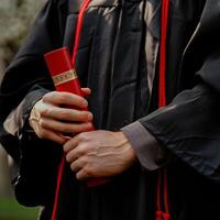 un' uomo indossare la laurea toga e Tenere diploma per cerimonia celebrazione. foto