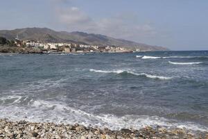 baia di Villaricos, ruvido mare, spiaggia, villaggio e montagne a il sfondo foto