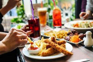 gruppo di persone mangiare cibo in giro un' tavolo foto