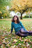 un' ragazza nel un' vestito con palloncini bugie su il terra coperto con autunno le foglie foto