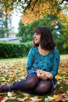 un' ragazza nel un' vestito con palloncini bugie su il terra coperto con autunno le foglie foto