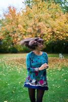 un' ragazza nel un' vestito con palloncini è giocando nel il autunno giardino foto