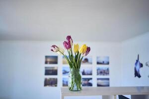 mazzo di multicolore tulipani nel un' trasparente vaso nel il interno foto