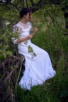 bellissimo donna nel bianca Vintage ▾ vestito con treno e Tenere Vintage ▾ specchio nel primavera giardino a tramonto foto