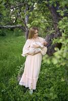 bellissimo madre è l'allattamento al seno sua bambino ragazza nel il giardino foto