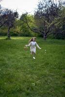 un' poco ragazza con lungo capelli corre attraverso il giardino con un' cestino pieno di fiori foto