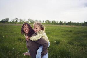 un' madre rotoli sua figlie su sua Indietro, giocando cavallo, baci e abbracci foto