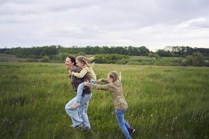 un' madre rotoli sua figlie su sua Indietro, giocando cavallo, baci e abbracci foto