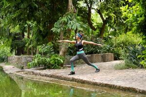 femmina esercizio virabhadrasana 2 yoga posa nel il parco foto