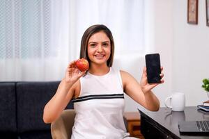 femmina modello mostrando Mela e mobile Telefono nero schermo su telecamera foto