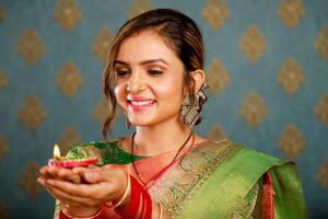 bella giovane modello nel tradizionale indiano abiti Tenere diya nel mano foto