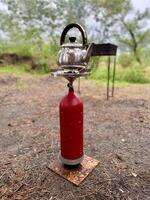 cottura a vapore cibo nel il foresta. tè su un' portatile gas stufa all'aperto. preparazione prima colazione per un' picnic durante un' escursione. viaggio campeggio stile di vita concetto. foto