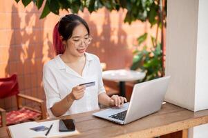 un' giovane positivo asiatico donna è registrazione sua credito carta su un' sito web, fabbricazione un in linea pagamento. foto