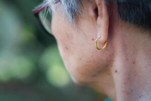 lato Visualizza di il viso di un anziano donna indossare un' d'oro orecchino. anziano e Salute cura concetto foto