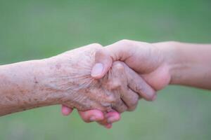 mani di un' anziano donna Tenere il mano di un' giovane donna. incoraggiamento concetto foto