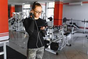 ritratto di giovane sportiva con smartphone ascoltando per musica nel Palestra foto