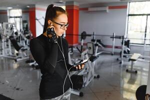 giovane sorridente donna ascoltando per musica su smartphone a il Palestra foto