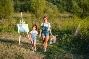 giovane madre e sua figlia avere divertimento, La madre di giorno. sorridente madre con bellissimo figlia disegna natura. foto