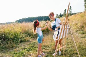 soleggiato natura, mamma e figlia dipingere un' immagine nel un' parco , pittura un' poco bambino, bambino creatività. La madre di giorno. foto