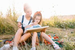 soleggiato natura, mamma e figlia dipingere un' immagine nel un' parco , pittura un' poco bambino, bambino creatività. La madre di giorno. foto