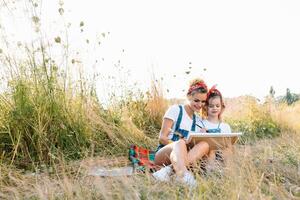 madre insegna figlia dipingere nel parco. soleggiato natura, mamma e figlia dipingere un' immagine nel un' parco , pittura un' poco bambino, bambino creatività. La madre di giorno. foto