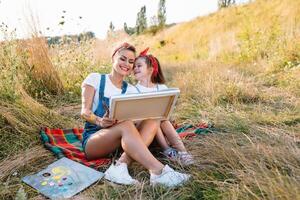 madre insegna figlia dipingere nel parco. soleggiato natura, mamma e figlia dipingere un' immagine nel un' parco , pittura un' poco bambino, bambino creatività. La madre di giorno. foto