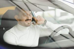 uomo che parla al cellulare mentre guida l'auto. foto