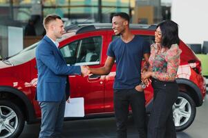 venditore mostrando nuovo auto per africano coppia nel showroom foto