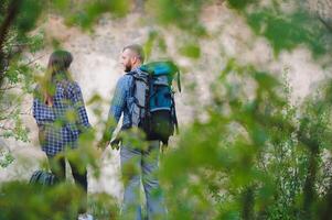 indietro Visualizza di giovane paio backpackers con grande zaini Tenere mani e a piedi lungo un' strada con bellissimo montagna paesaggio su sfondo. foto