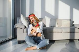 allegro giovane donna Tenere sua grande cucciolo con nero naso e ridendo. interno ritratto di sorridente ragazza in posa con francese bulldog foto