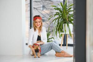 allegro giovane donna Tenere sua grande cucciolo con nero naso e ridendo. interno ritratto di sorridente ragazza in posa con francese bulldog foto